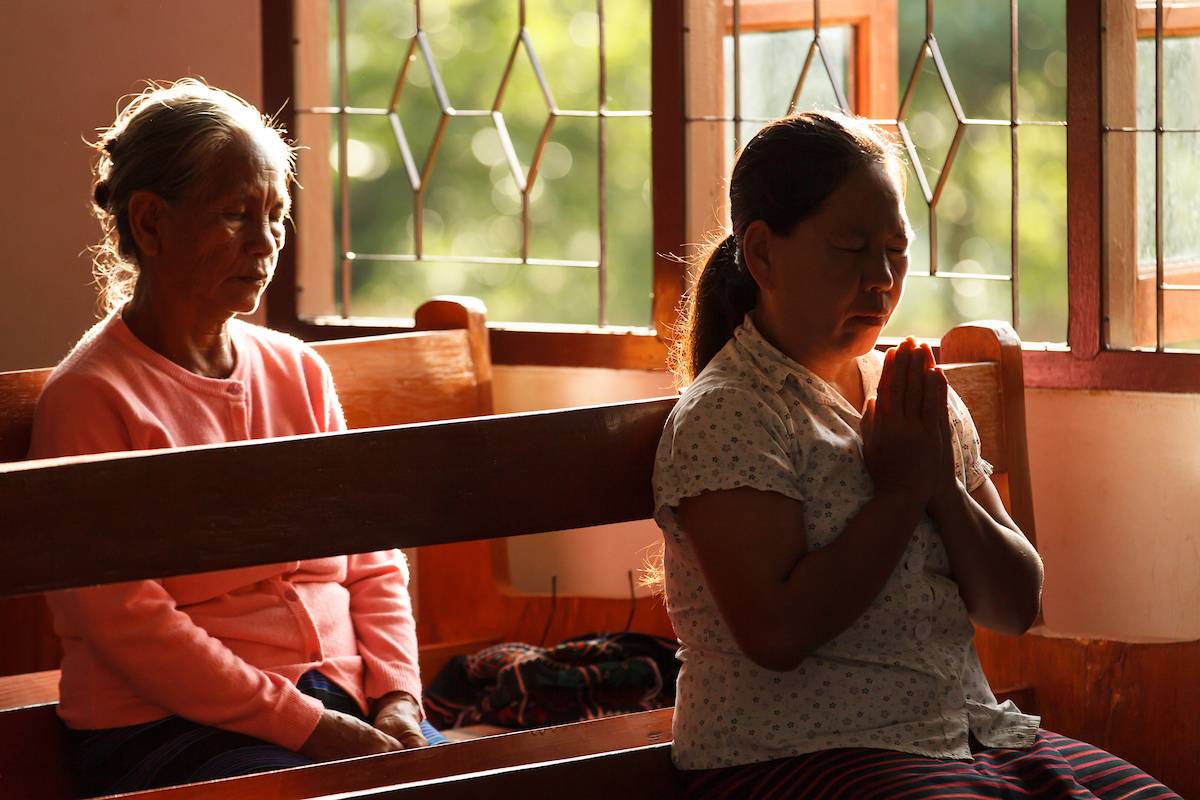Two women praying during a church service.